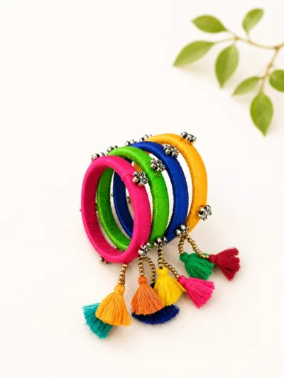 Handmade colorful thread work bangles set with tassel hangings and decorative metal embellishments for festive and ethnic wear.
