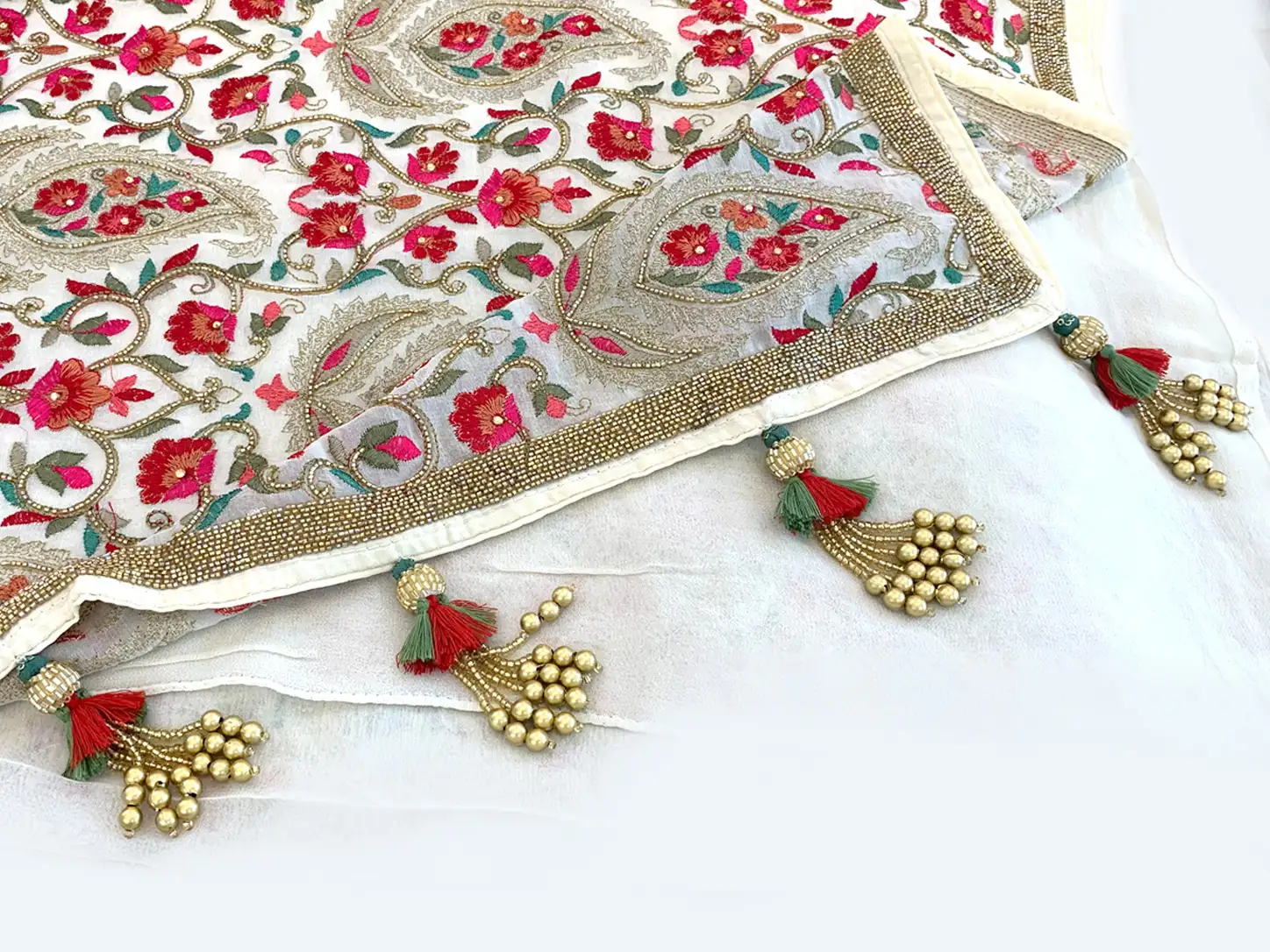Handmade floral saree pallu tassels with red and sage green thread accents, decorative beads, and golden pearl drop clusters attached to an embroidered saree border.
